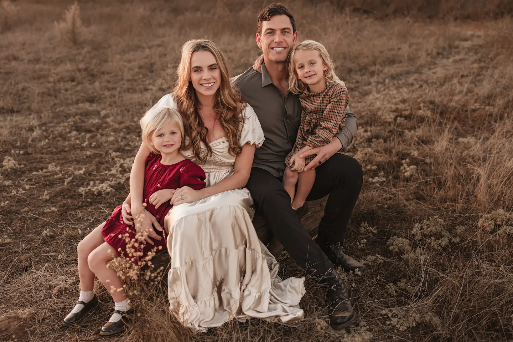 The Johnston family, owners of JJ's Fence Company, sitting together in a field, smiling at the camera